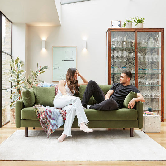 two people sitting on a green velvet sofa